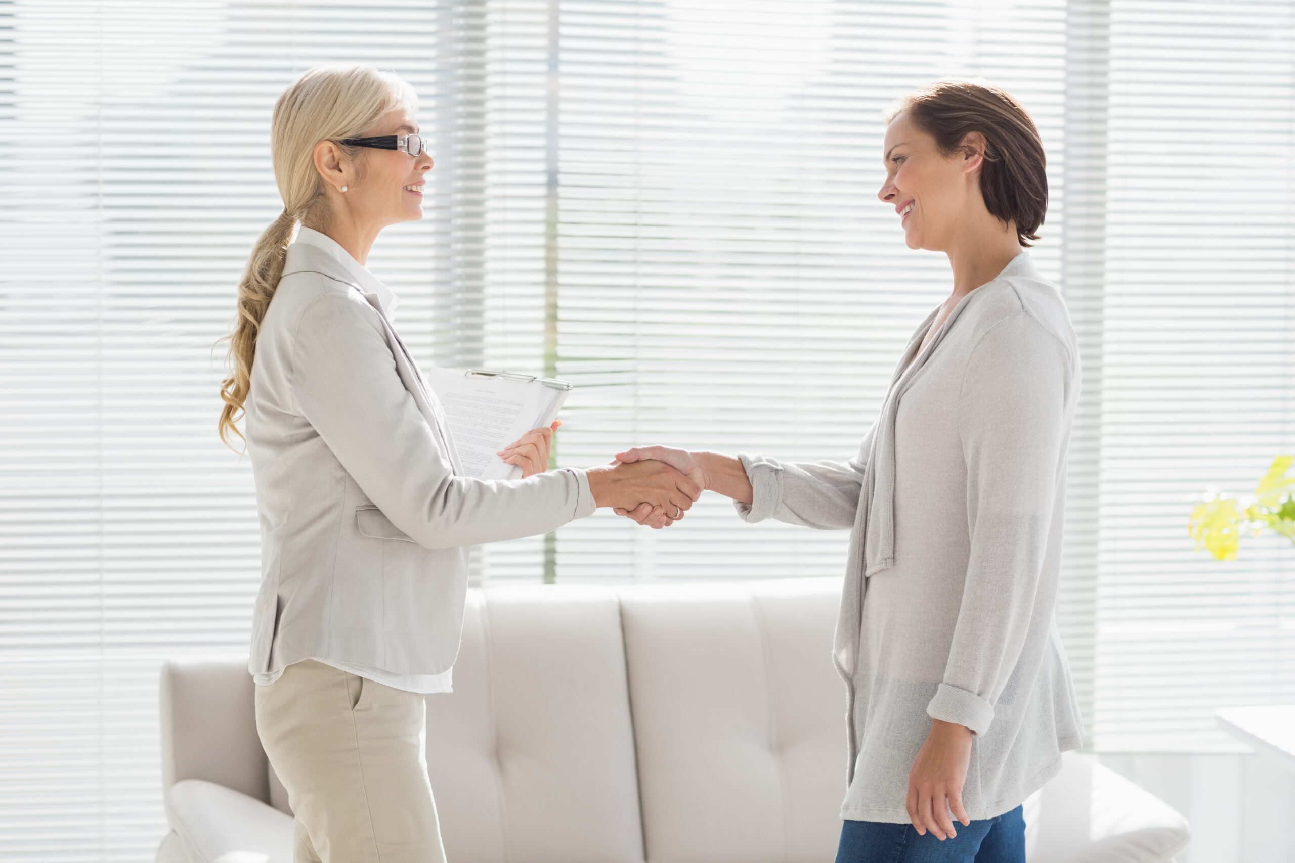 Smiling woman and therapist shaking hands at home Smiling woman and therapist shaking hands at home